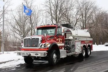 Front-left exterior view of tanker truck showing long hood cab and polished tank body
