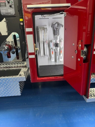 Narrow open compartment showing mounted hand tools and storage hooks