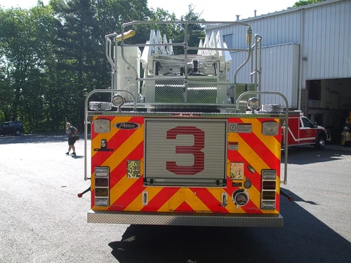 Straight rear view with red-yellow chevrons, rear platform railing, and center rear compartment door.