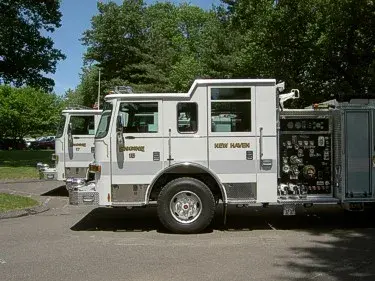 Left-side profile of one pumper showing cab, pump panel controls, and side compartment layout.
