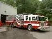 Wide front right view of the parked tower ladder near the shop building.