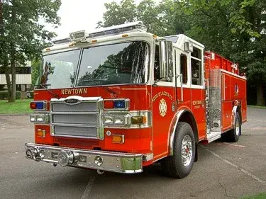 Front-left exterior view of pumper showing grille, bumper, and side body compartments