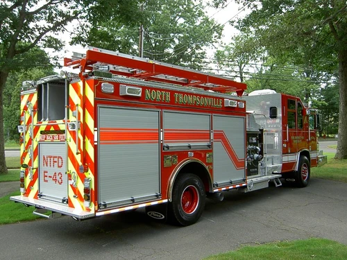 Rear-left exterior view showing chevrons, side hosebed rails, and rear wheel area