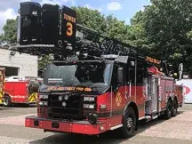 Pierce Ascendant tower ladder front-left view showing bucket, aerial sections, and side compartments