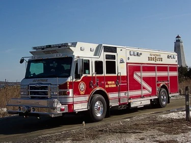 Front-left exterior view of a rescue truck showing chrome bumper, cab, and long side compartment body.