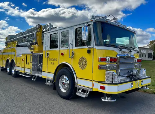 Tower ladder truck front-right exterior view showing cab, bumper, and ladder sections above