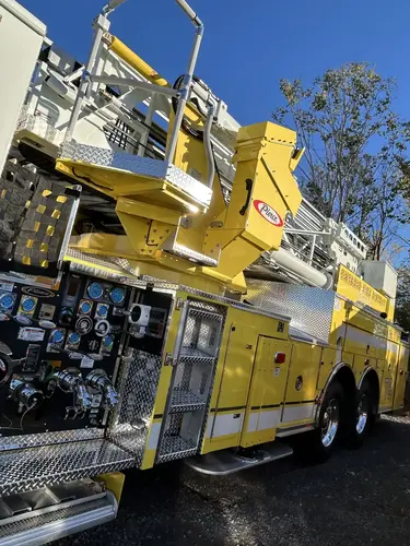 Officer-side profile view showing ladder bed, side compartments, and tandem rear wheels