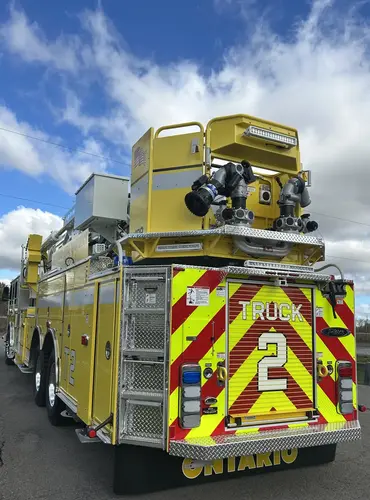Rear view showing red-and-yellow chevrons, rear lights, and aerial boom above