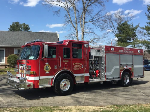 Front-left exterior view showing pumper cab, wheel area, and pump panel section