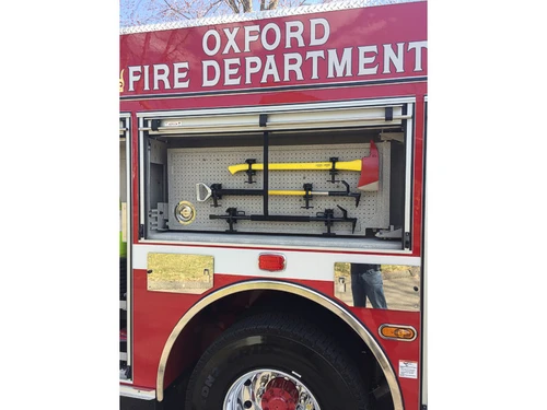 Open side tool-board compartment showing pike poles and shovels over rear wheel area