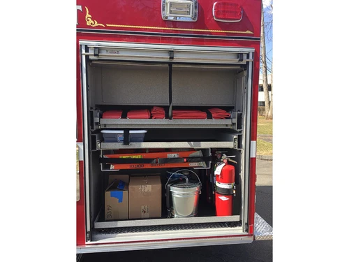 Open rear-side compartment showing folded hose, fire extinguisher, and tool storage