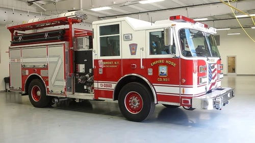 Front-right exterior view of a squad pumper showing the cab, side pump panel area, and rear body compartments.