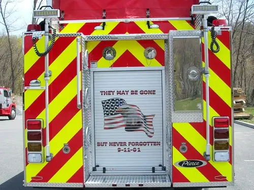 Rear close-up view with red-yellow chevrons, rear roll-up door graphic, and scene lights.