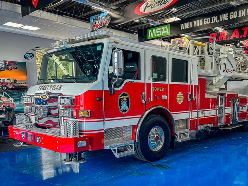 Tower ladder front-left exterior view showing enclosed cab and aerial device above
