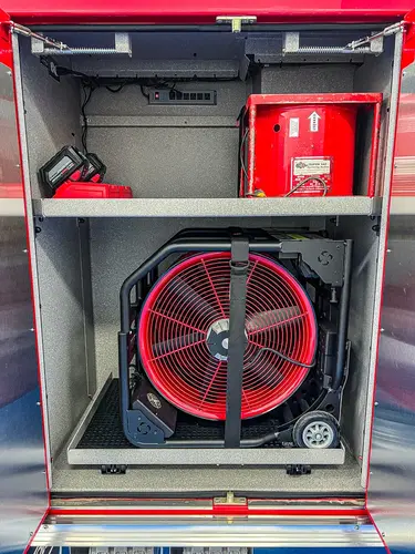 Open compartment showing a portable ventilation fan and shelf storage