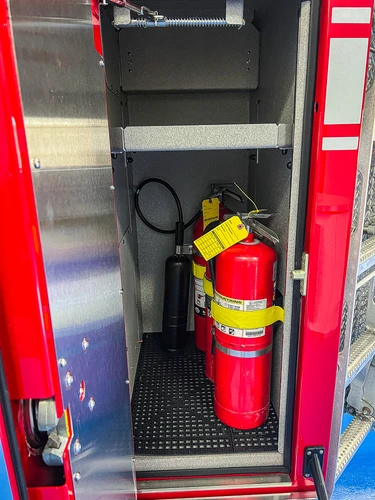 Open narrow compartment showing a mounted extinguisher and lower storage space