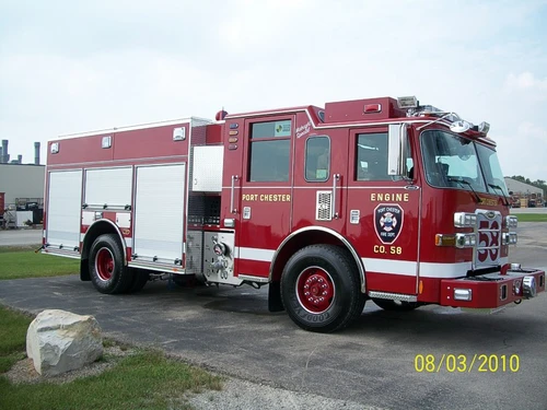 Front-right exterior view of a pumper showing the enclosed cab, side pump panel section, and body compartments.