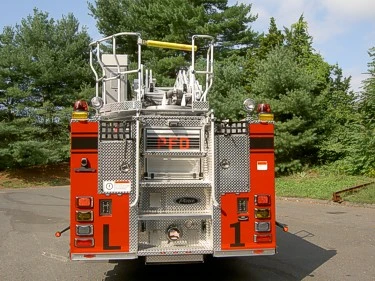 Straight rear view showing rear access platform, warning lights, and rear compartment panels.