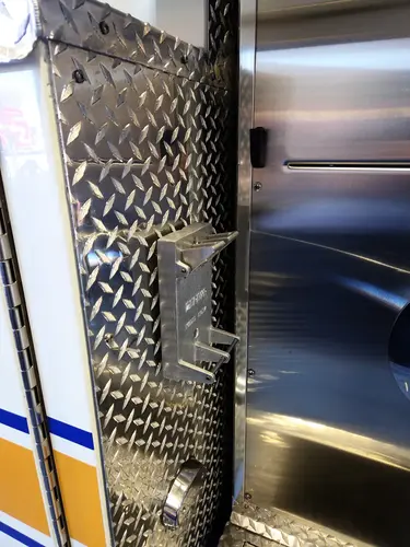 Diamond-plate body close-up showing mounted bracket and adjacent compartment panel