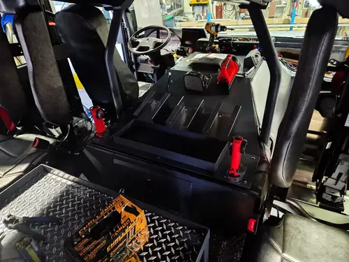 Cab interior rear-to-front view showing center console, steering wheel, and seat mounts