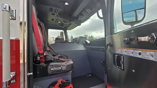 Cab interior officer-side view showing front seat, dashboard shelf, and overhead controls