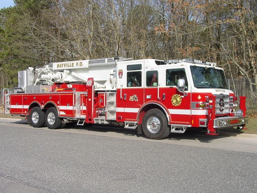 Front-right side view highlighting the cab, side compartments, and stowed aerial ladder bed.