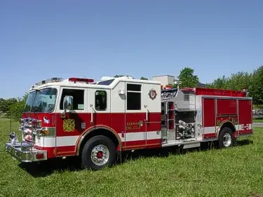 Front-right wide view showing the cab, pump panel controls, side compartments, and rear wheel area.