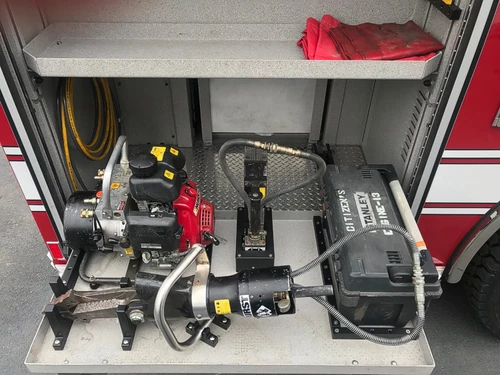 Open side compartment showing mounted rescue tool and hose fittings