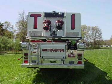 Straight rear view showing rear stabilizers, rear compartments, and bucket-mounted waterway fittings.