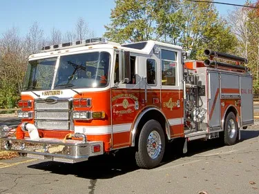 Front-left exterior view of pumper showing grille, bumper, and side pump panel