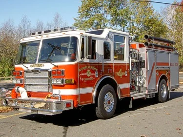 Front-left exterior view of pumper showing grille, bumper, and side pump panel