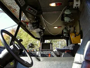 Driver cockpit interior view showing steering wheel, console, and dashboard monitors