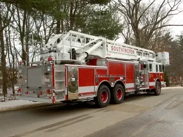 Rear-right exterior view showing the stowed aerial ladder, rear body compartments, and tandem wheel area.