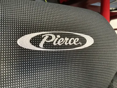 Seatback close-up showing Pierce logo on dark fabric
