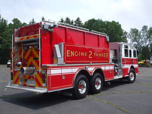 Rear-left exterior view of tanker pumper showing chevrons, rear discharge, and tandem rear axles
