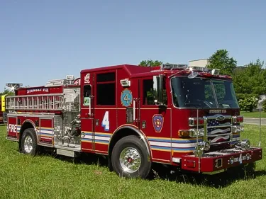 Pumper front-left exterior view on grass showing enclosed cab and side compartments