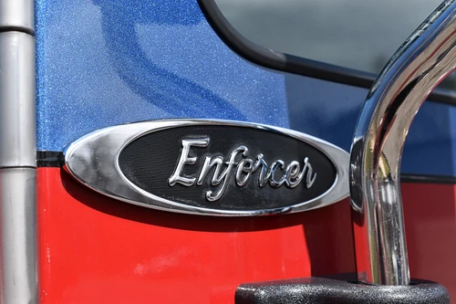 Body badge close-up showing Enforcer emblem on blue and red panel