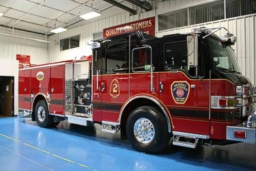 Front left indoor view of a pumper with chrome bumper, cab lights, and side compartment body.