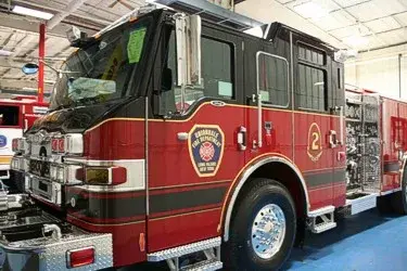 Close front left cab view showing door emblem, mirror, front wheel, and pump panel area behind the cab.