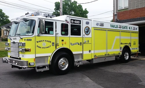 Front-left exterior view of a rescue pumper showing the enclosed cab, side compartments, and rear body section.