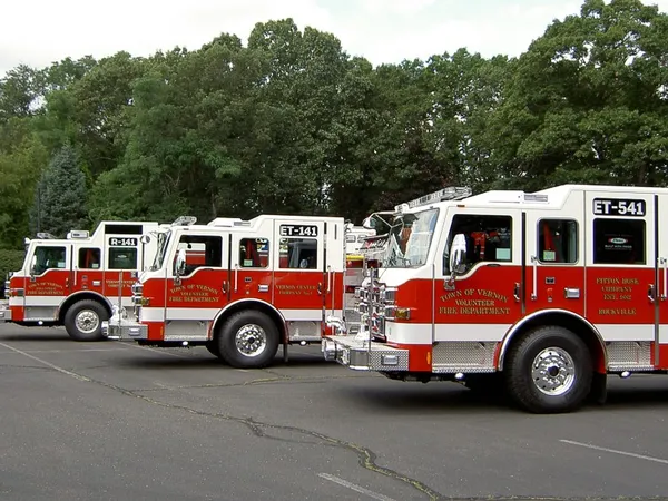 Pumper lineup side view showing multiple red-and-white apparatus parked in lot