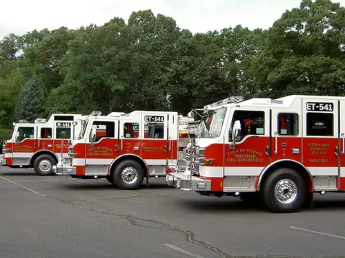Pumper lineup side view showing multiple red-and-white apparatus parked in lot