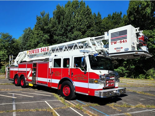 Tower ladder truck front-left exterior view showing aerial sections and cab