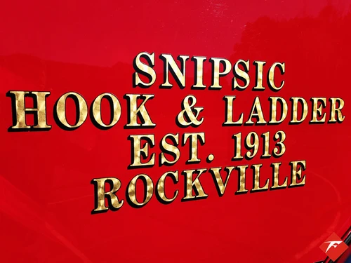 Body panel close-up showing gold company lettering on red paint