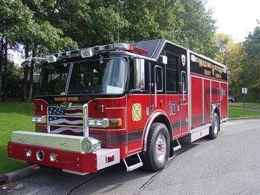 Front-left exterior view of a heavy rescue pumper with enclosed cab, side compartments, and rear body.