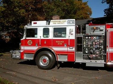 Driver-side cab and pump panel close-up showing gauges, valve controls, and front wheel area.