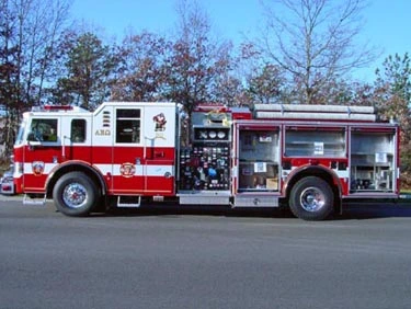Driver-side profile showing exposed pump panel, open compartments, and wheel area