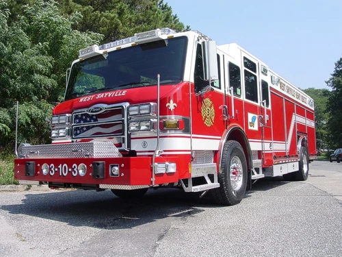 Low front-left angle showing grille, bumper, warning lights, and side body profile.