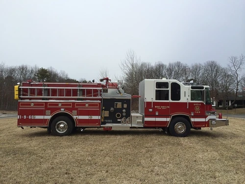 Driver-side profile view with pump panel controls, side ladder storage, and wheel/tire area.