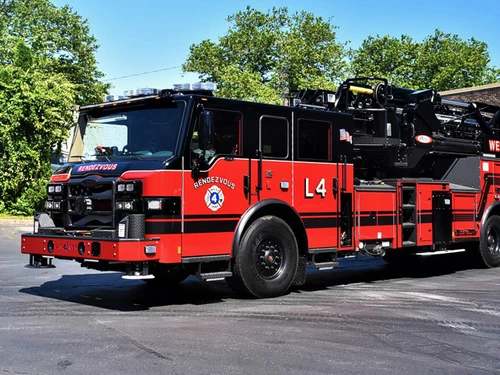 Tower ladder truck front-left exterior view showing enclosed cab and ladder structure